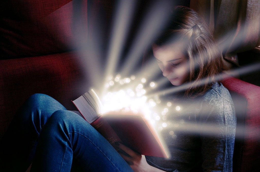 beautiful light shines from a book a girl is reading in her lap